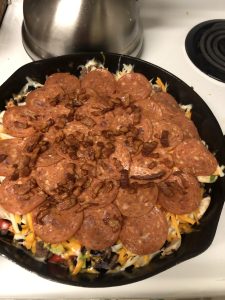 Skillet pizza topped with pepperoni, cheese, and crispy bacon bits.