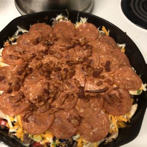 Skillet pizza topped with pepperoni, cheese, and crispy bacon bits.