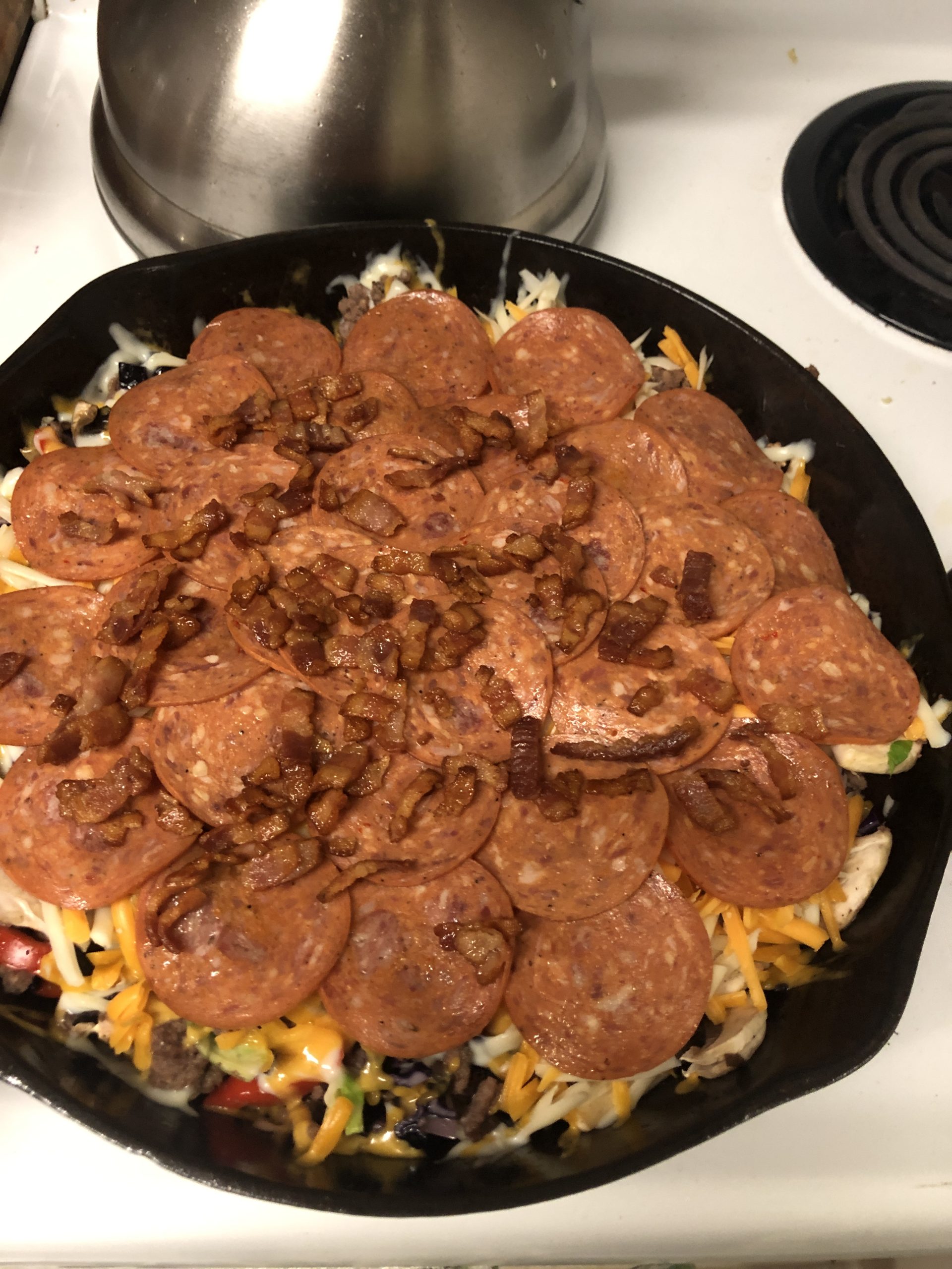 Skillet pizza topped with pepperoni, cheese, and crispy bacon bits.