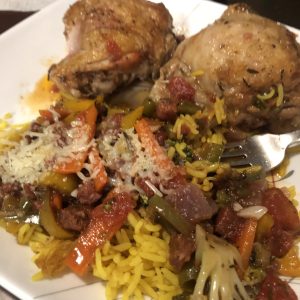 Delicious chicken with vibrant roasted vegetables and fragrant yellow rice, garnished with cheese.