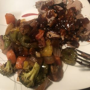 Savor the Rogue's rich beef slices drizzled with spicy sauce, flanked by vibrant roasted vegetables.