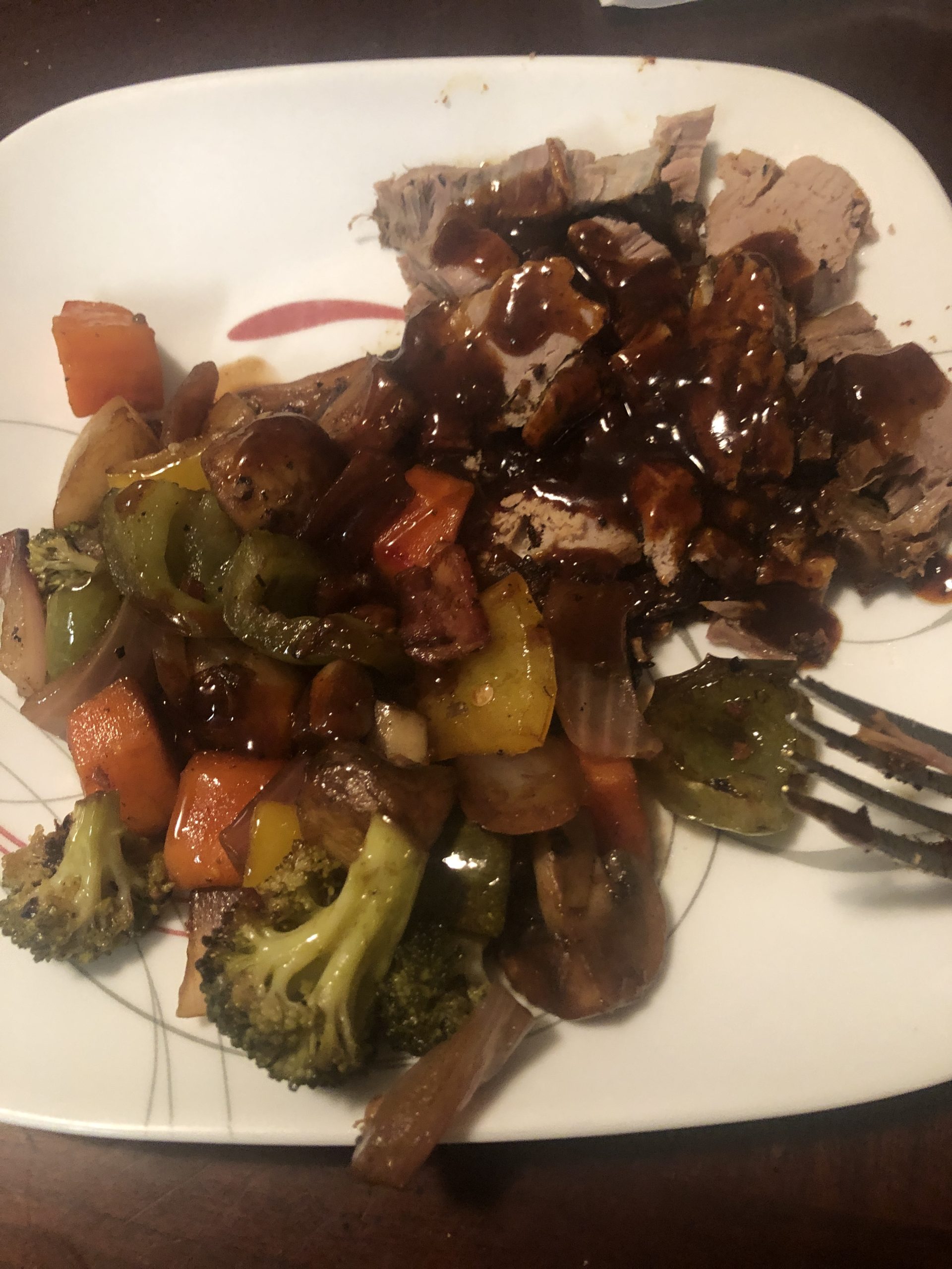 Savor the Rogue's rich beef slices drizzled with spicy sauce, flanked by vibrant roasted vegetables.