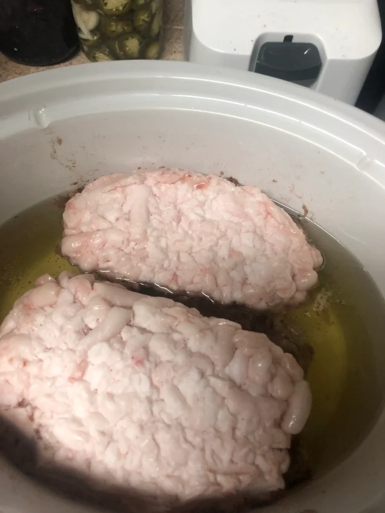 Rich, creamy tallow rendering in a slow cooker, surrounded by jars of pickled treats, evoking homestead abundance.