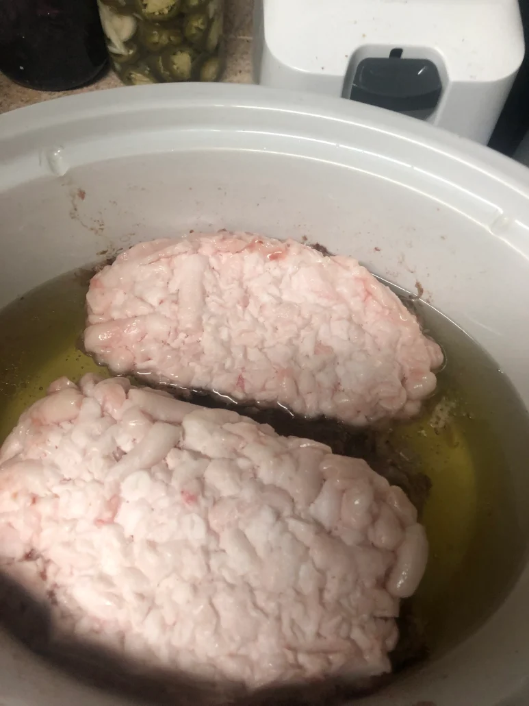 Rich, creamy tallow rendering in a slow cooker, surrounded by jars of pickled treats, evoking homestead abundance.