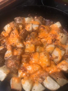 Golden, cheesy roasted potatoes with crispy edges and melted cheese in a pan.