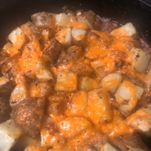 Golden, cheesy roasted potatoes with crispy edges and melted cheese in a pan.