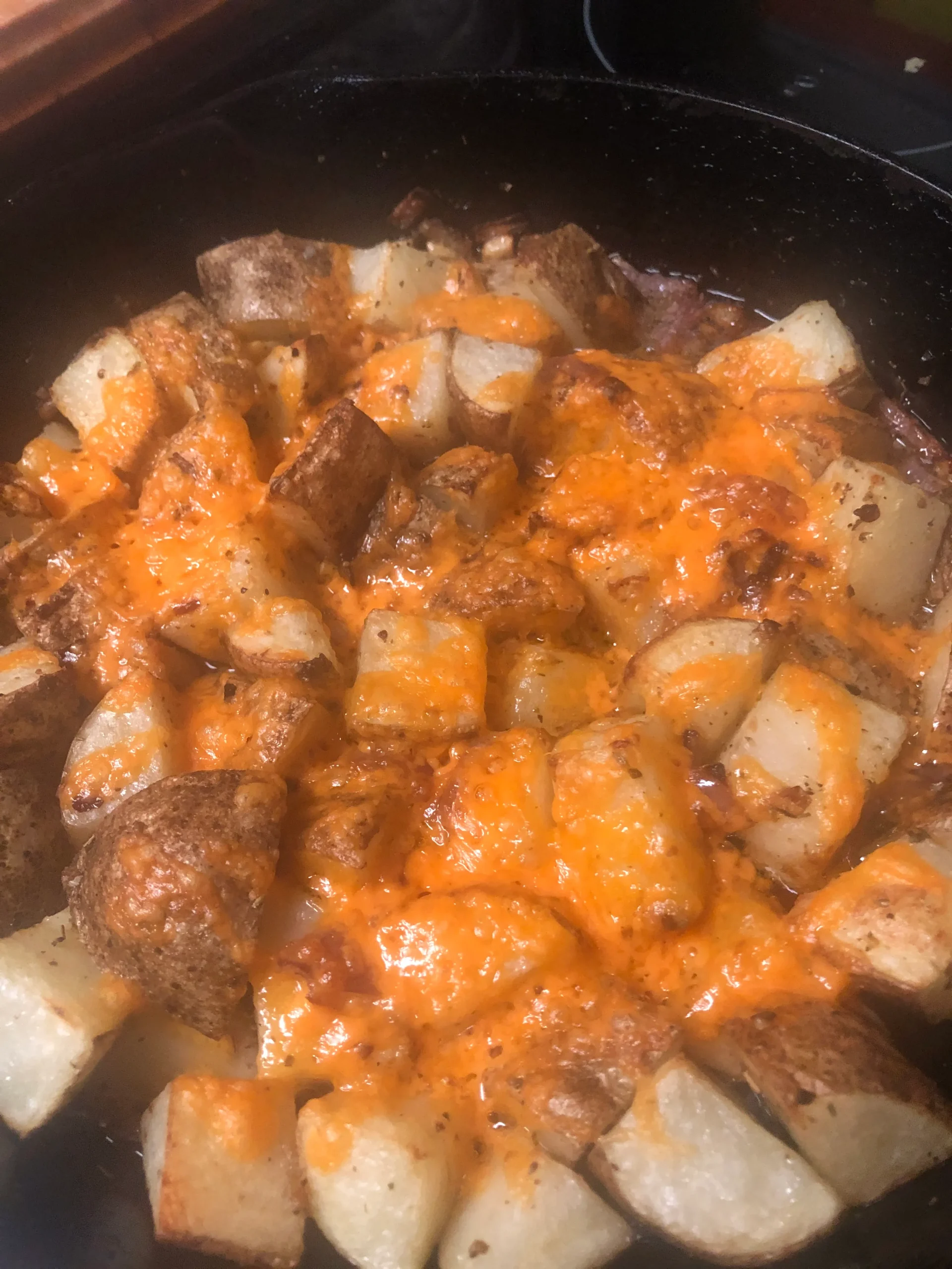 Golden, cheesy roasted potatoes with crispy edges and melted cheese in a pan.