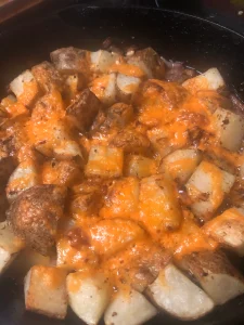 Golden cheesy roasted potatoes in a cast-iron skillet, ready to serve.