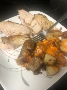 Succulent sliced chicken and roasted potatoes drizzled in vibrant sauce on a decorative plate.