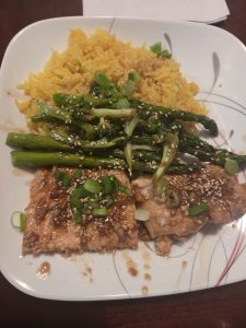 A tantalizing plate featuring soy-glazed salmon, vibrant turmeric rice, and sesame-sprinkled asparagus and broccoli.